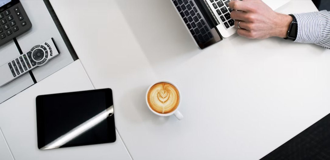 A desk with a laptop, tablet and coffee